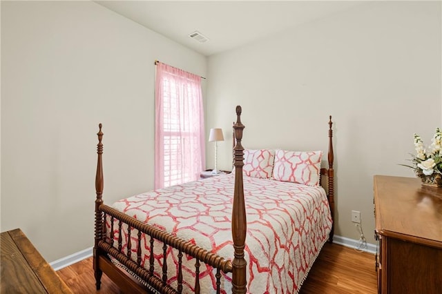 bedroom with visible vents, baseboards, and wood finished floors