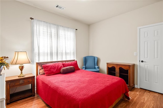 bedroom featuring wood finished floors and visible vents