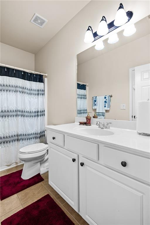 full bathroom with tile patterned floors, visible vents, toilet, a shower with curtain, and vanity