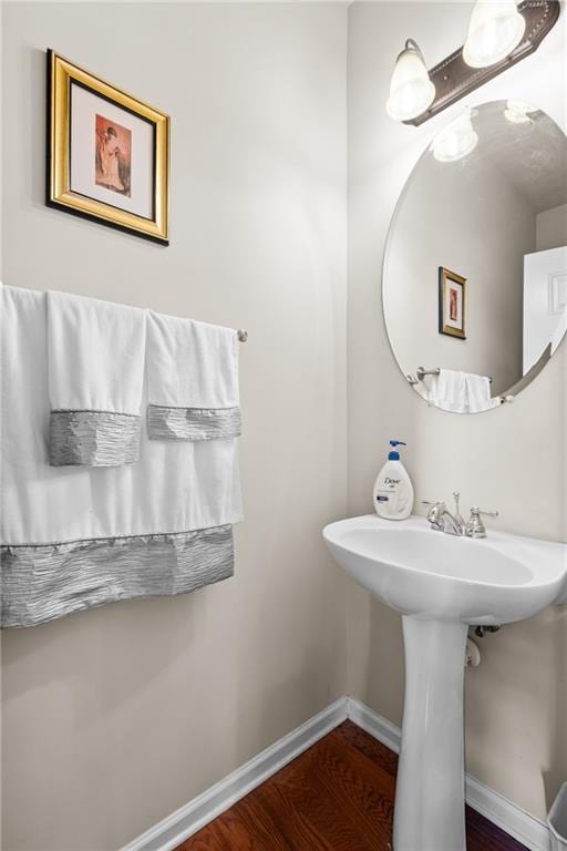 bathroom with a sink, baseboards, and wood finished floors