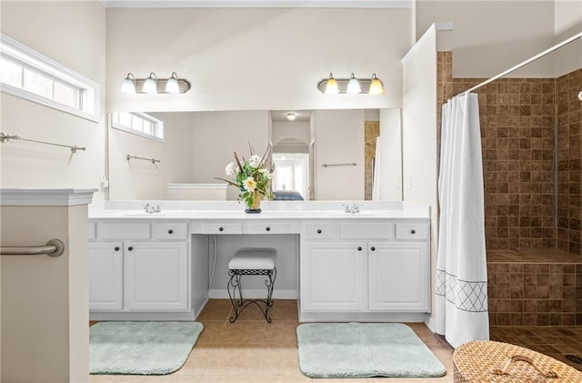 full bath with tile patterned floors, double vanity, a tile shower, and a sink