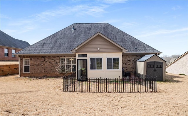 back of house with brick siding, a storage unit, fence, and a shingled roof