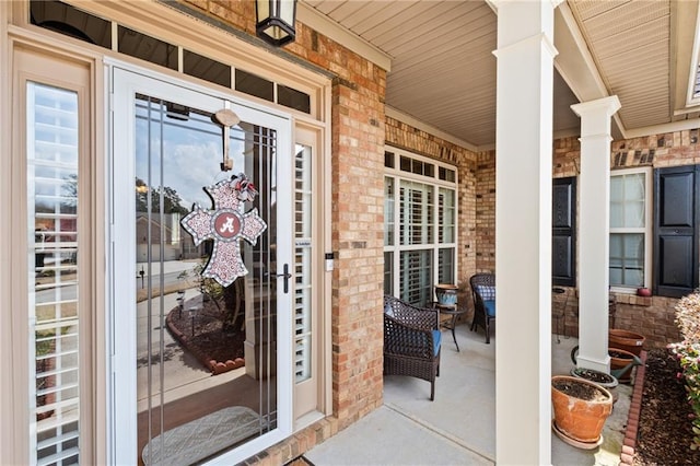 view of exterior entry with brick siding and covered porch