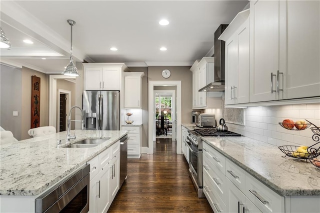 kitchen featuring wall chimney range hood, ornamental molding, a sink, decorative backsplash, and appliances with stainless steel finishes
