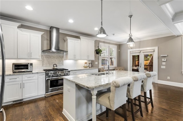 kitchen with wall chimney exhaust hood, a toaster, a sink, decorative backsplash, and stainless steel stove