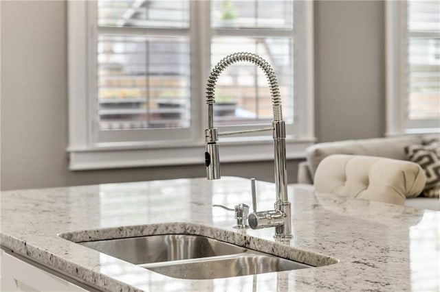 interior details with white cabinetry, light stone countertops, and a sink