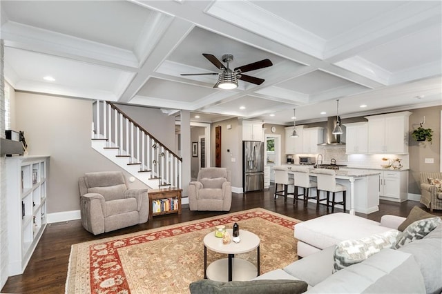 living room featuring dark wood-style floors, baseboards, coffered ceiling, stairs, and ceiling fan