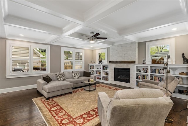 living room featuring dark wood-style floors, a ceiling fan, beamed ceiling, baseboards, and a fireplace
