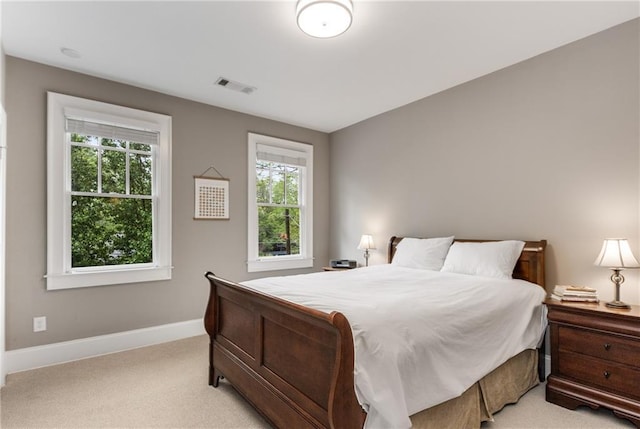bedroom with visible vents, baseboards, light colored carpet, and multiple windows