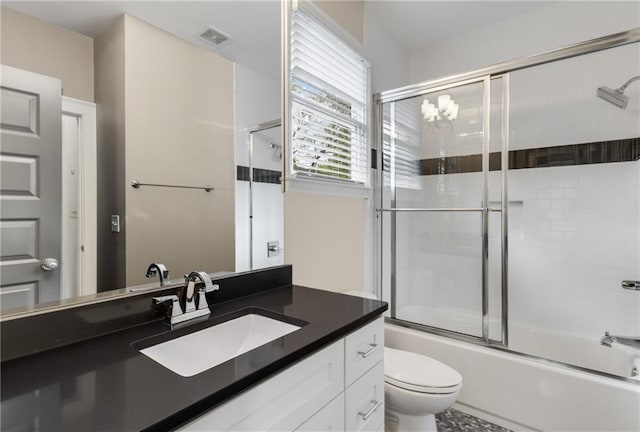 bathroom featuring visible vents, enclosed tub / shower combo, vanity, and toilet