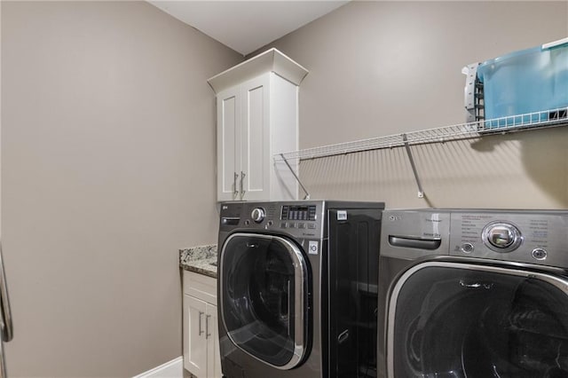 laundry area with washing machine and dryer, baseboards, and cabinet space