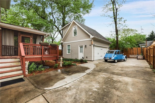 view of side of home featuring fence, a wooden deck, and driveway