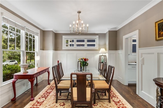 dining space with dark wood-type flooring, a decorative wall, a notable chandelier, and wainscoting
