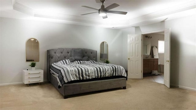 carpeted bedroom with a tray ceiling, ensuite bath, ceiling fan, and ornamental molding