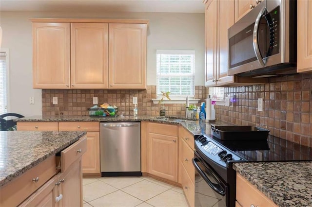 kitchen with appliances with stainless steel finishes, light brown cabinets, tasteful backsplash, and dark stone countertops