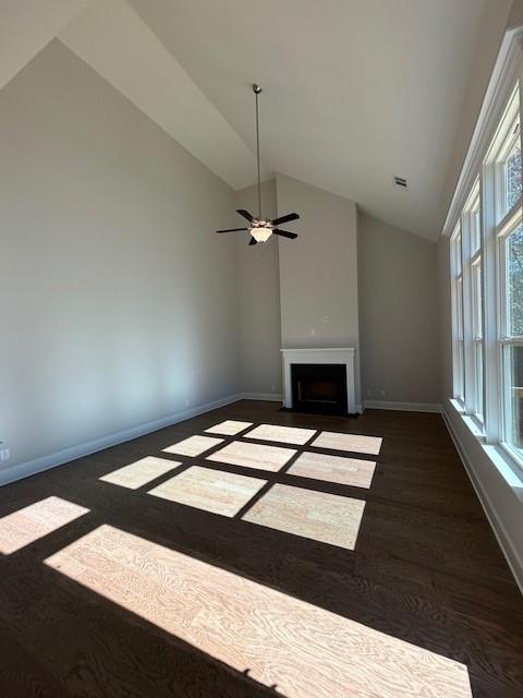 unfurnished living room with ceiling fan, dark hardwood / wood-style floors, and vaulted ceiling