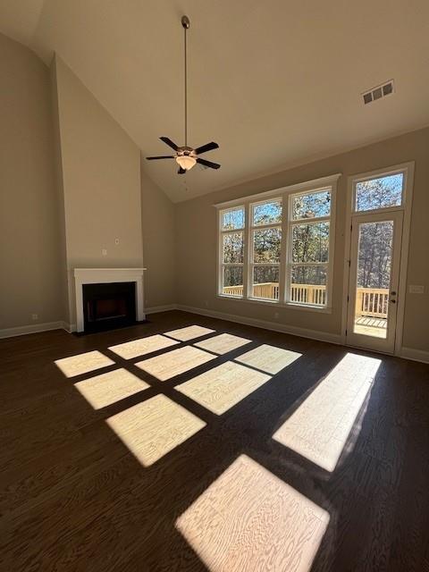 unfurnished living room with vaulted ceiling, ceiling fan, and dark wood-type flooring