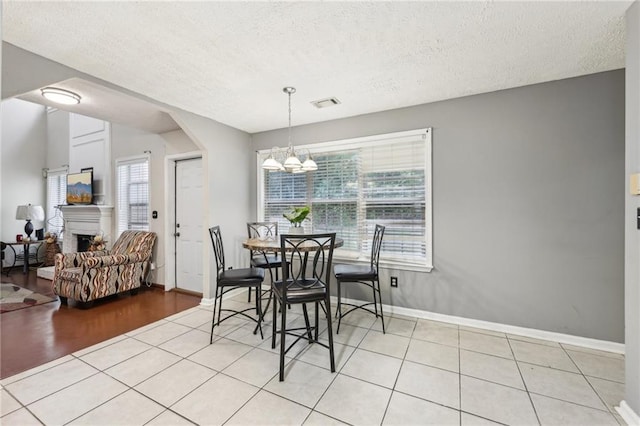 250 Kensington Trce, Stockbridge, GA 30281 - dining area with a chandelier, a textured ceiling, light tile patterned floors, baseboards, and a fireplace