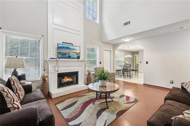 250 Kensington Trce, Stockbridge, GA 30281 - living room featuring a towering ceiling, a brick fireplace, wood finished floors, and a chandelier