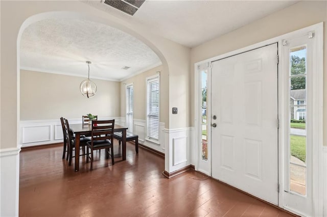 250 Kensington Trce, Stockbridge, GA 30281 - foyer entrance with arched walkways, a textured ceiling, a wainscoted wall, dark wood finished floors, and a decorative wall