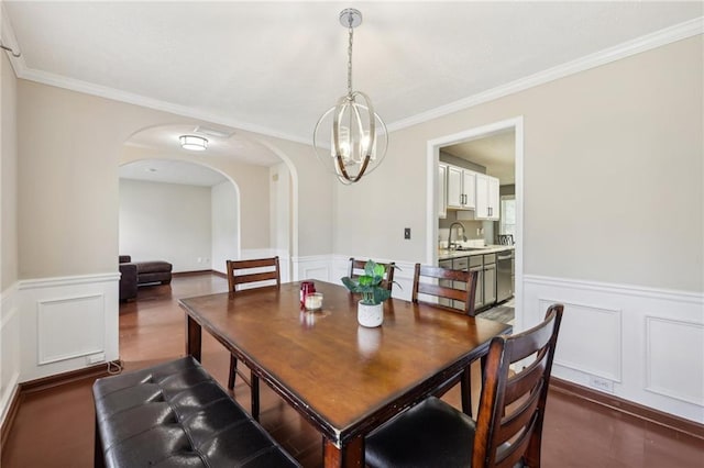 250 Kensington Trce, Stockbridge, GA 30281 - dining room featuring a wainscoted wall, a decorative wall, arched walkways, a chandelier, and crown molding