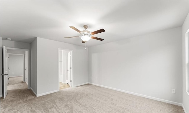 unfurnished bedroom featuring ceiling fan, ensuite bath, baseboards, and light carpet