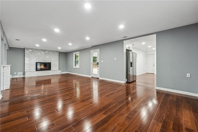 unfurnished living room with a high end fireplace and dark wood-type flooring