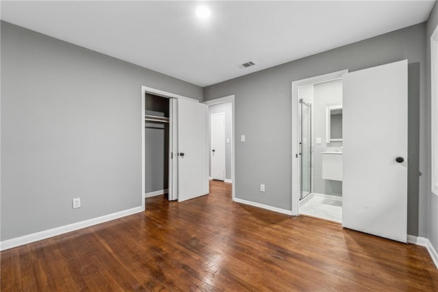 unfurnished bedroom with dark hardwood / wood-style flooring, connected bathroom, and a closet