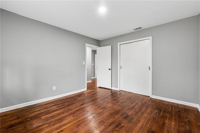 unfurnished bedroom with a closet and dark wood-type flooring