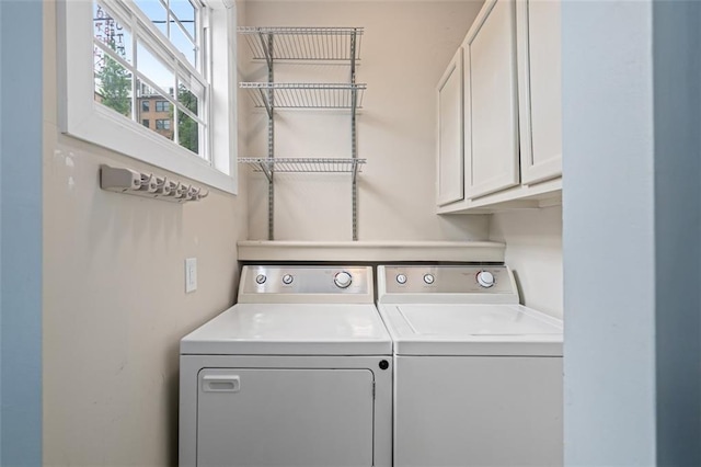 clothes washing area featuring cabinet space and separate washer and dryer