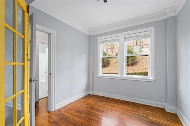spare room featuring baseboards, ornamental molding, and dark wood-type flooring