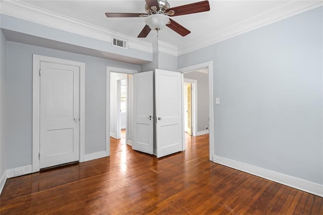 unfurnished bedroom featuring crown molding, ceiling fan, baseboards, wood finished floors, and visible vents