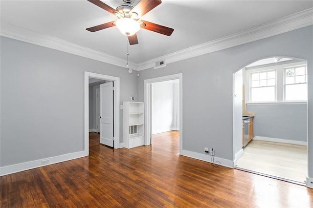 interior space with visible vents, a ceiling fan, crown molding, wood finished floors, and arched walkways