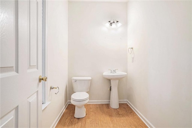 bathroom with wood finished floors, toilet, and baseboards