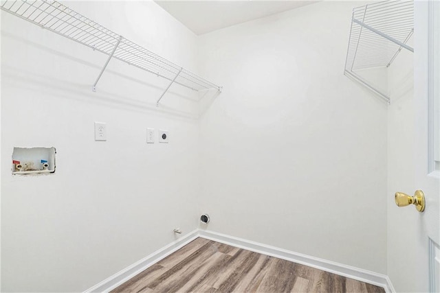 clothes washing area with hookup for an electric dryer, washer hookup, baseboards, wood finished floors, and gas dryer hookup
