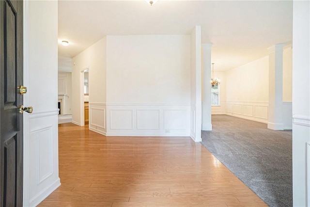 hall featuring a chandelier, a decorative wall, wood finished floors, and wainscoting