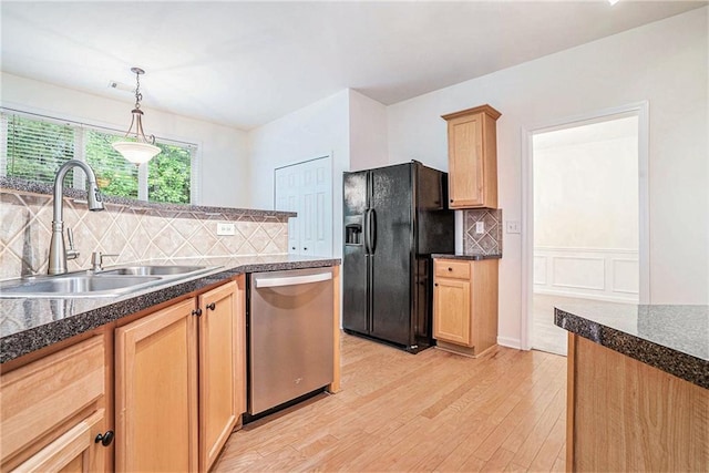kitchen with stainless steel dishwasher, black refrigerator with ice dispenser, a sink, light wood-style floors, and dark countertops