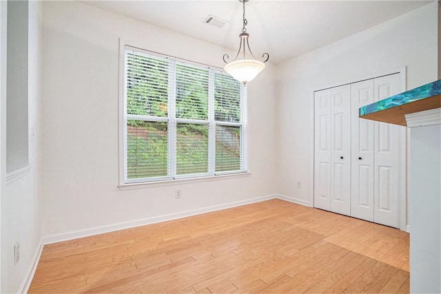 unfurnished dining area featuring light wood-style flooring and baseboards