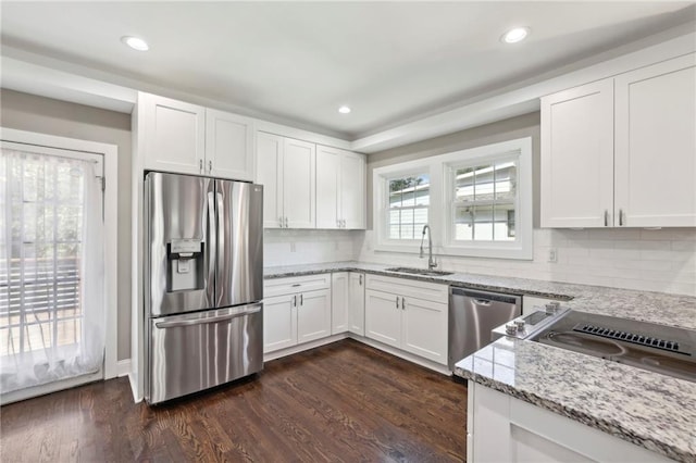 kitchen with stainless steel appliances, sink, white cabinets, light stone counters, and dark hardwood / wood-style flooring