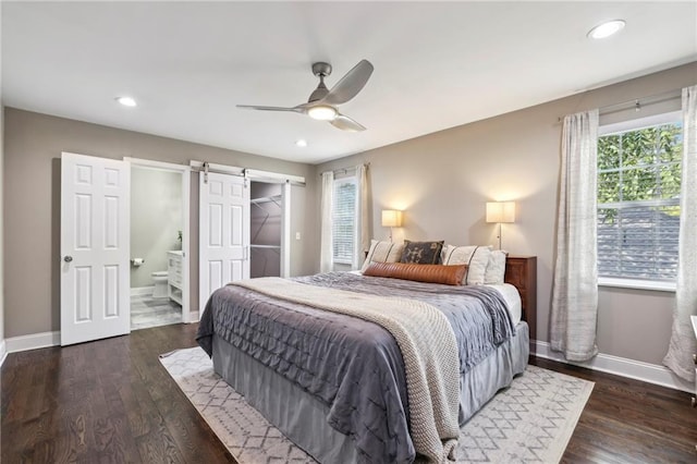 bedroom with multiple windows, ceiling fan, a barn door, and dark hardwood / wood-style floors