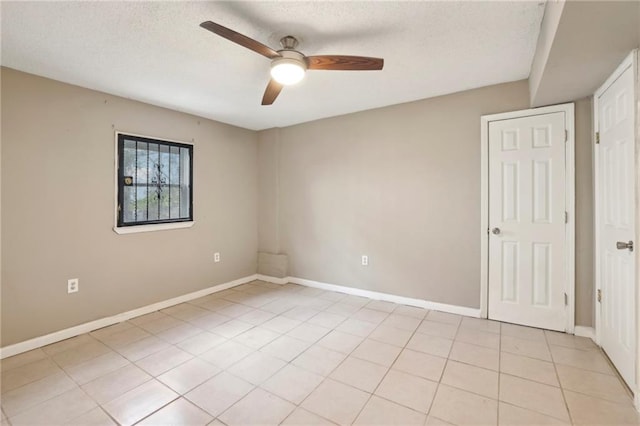 tiled spare room featuring a textured ceiling and ceiling fan