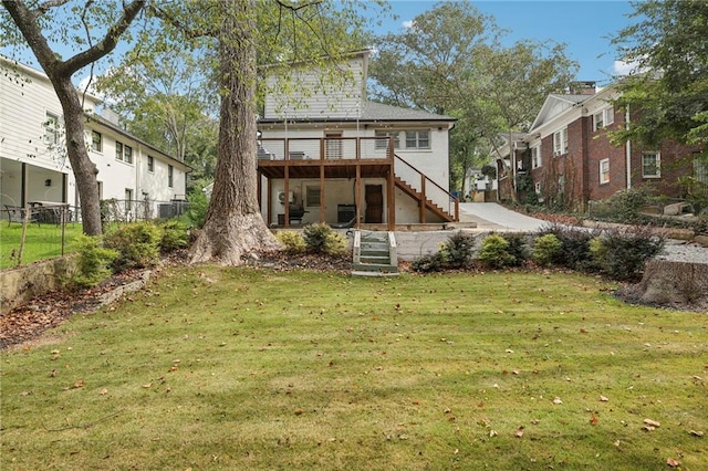 rear view of house featuring a lawn and a wooden deck