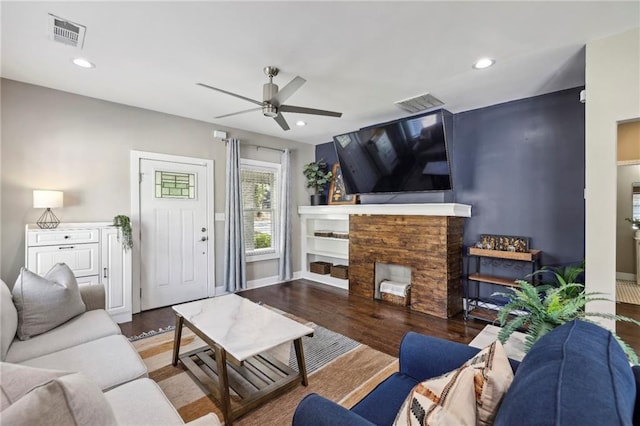 living room featuring ceiling fan, dark wood-type flooring, and a fireplace