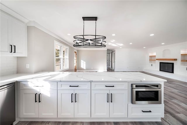 kitchen with pendant lighting, backsplash, stainless steel appliances, light stone counters, and white cabinets