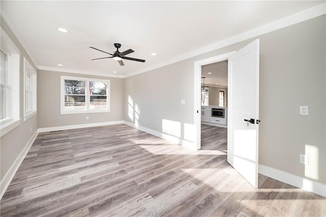 spare room with crown molding, plenty of natural light, ceiling fan, and light wood-type flooring