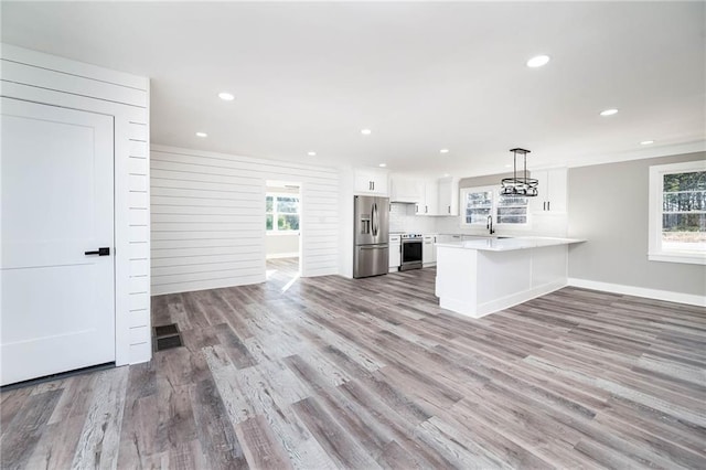 kitchen featuring pendant lighting, stainless steel appliances, light hardwood / wood-style floors, white cabinets, and kitchen peninsula