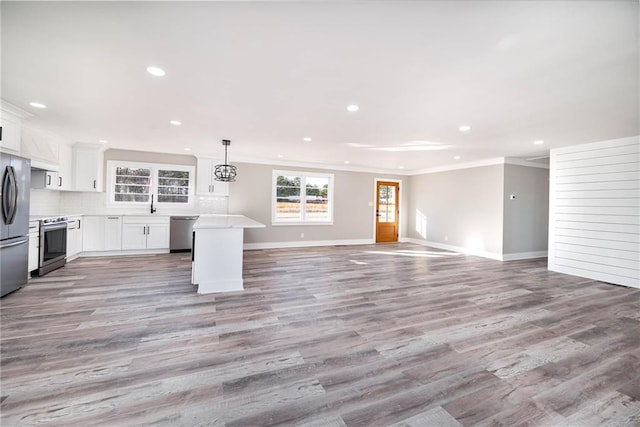 kitchen featuring white cabinetry, hanging light fixtures, light hardwood / wood-style flooring, and stainless steel appliances