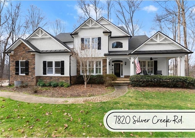 craftsman-style house featuring covered porch, stone siding, and a front lawn