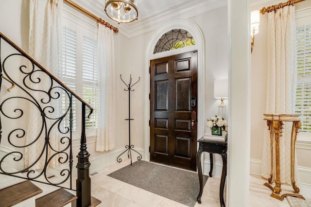 foyer entrance with an inviting chandelier, ornamental molding, and light tile patterned floors