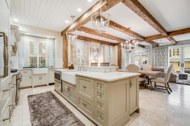 kitchen with sink, hanging light fixtures, a kitchen island with sink, an inviting chandelier, and french doors